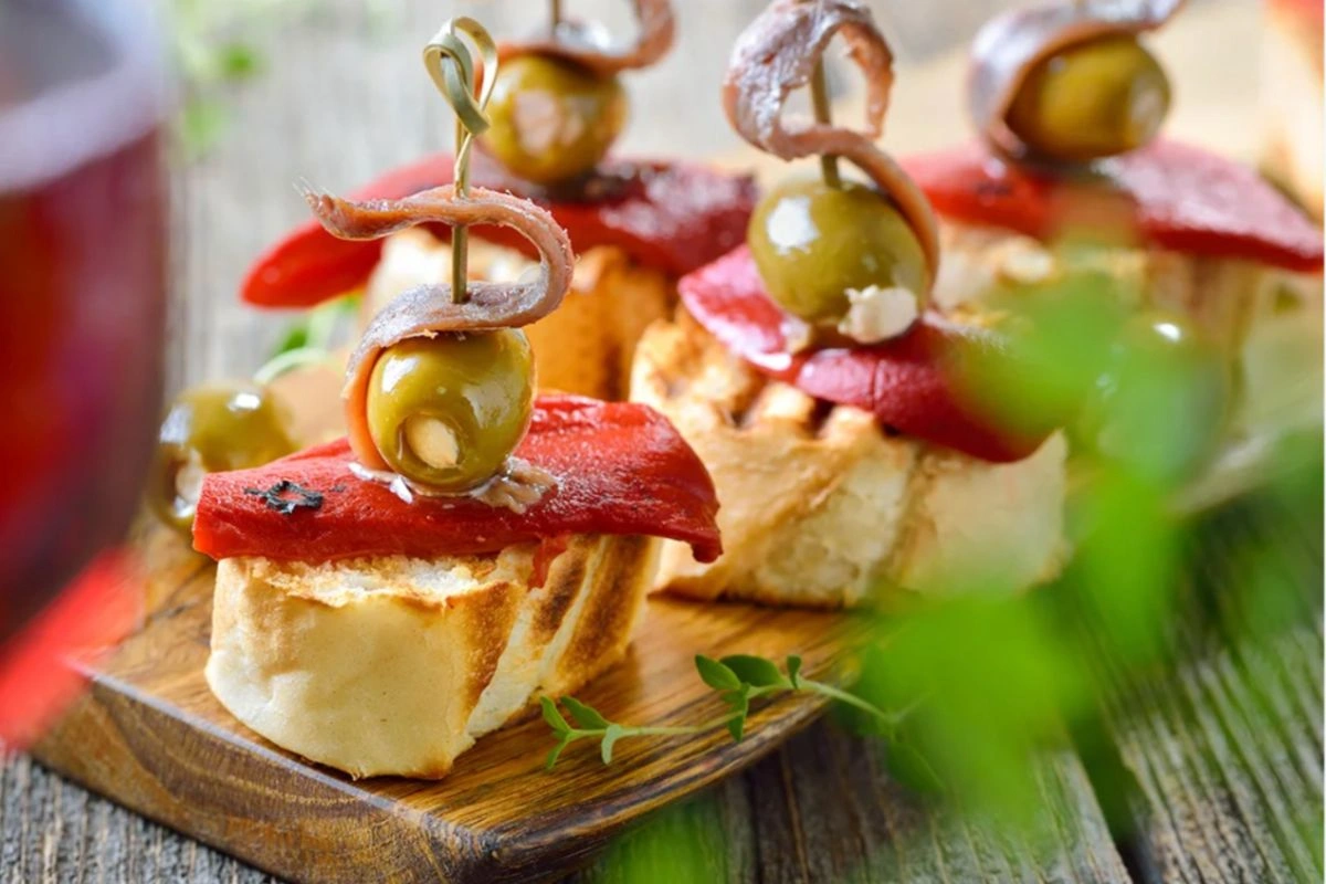 Delightful grilled cheese impaled with a piece of Iberian ham accompanied with olives